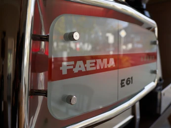 Weinbar 36_Kaffeespezialitäten Große FAEMA E61 Espressomaschine aus Edelstahl, reflektiert Umgebungsdetails im glänzenden Gehäuse.