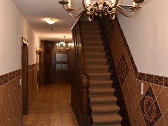 Flur und Treppe zum OG.JPG Flur mit heller Beleuchtung, keramischen Bodenfliesen, Wandverkleidungen und Treppe mit Teppichläufer.