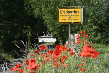 landlicher Ortseingang.JPG Ortseingangsschild von Kirchborchen, umgeben von leuchtend roten Mohnblumen und grüner Natur.