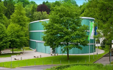 Außenansicht Neanderthal Museum in Mettmann Neanderthal Museum in Mettmann, moderne Glasarchitektur, umgeben von üppigem Grün und einem Spazierweg.