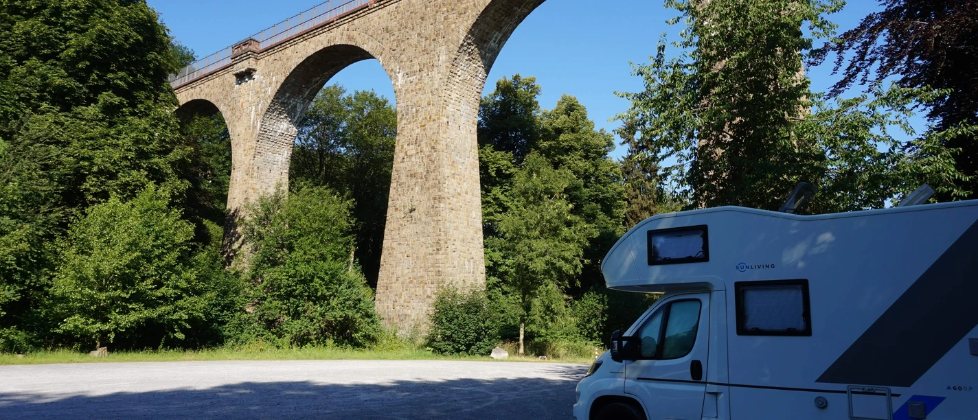 Wohnmobilstellplatz Saubrücke in Velbert Wohnmobilstellplatz nahe der Saubrücke in Velbert, umgeben von grünem Wald und beeindruckendem Viadukt.