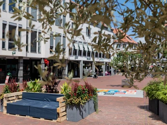 Sommeraktion Eine belebte Fußgängerzone mit gemütlicher Sitzecke aus Paletten und Pflanzendekorationen.