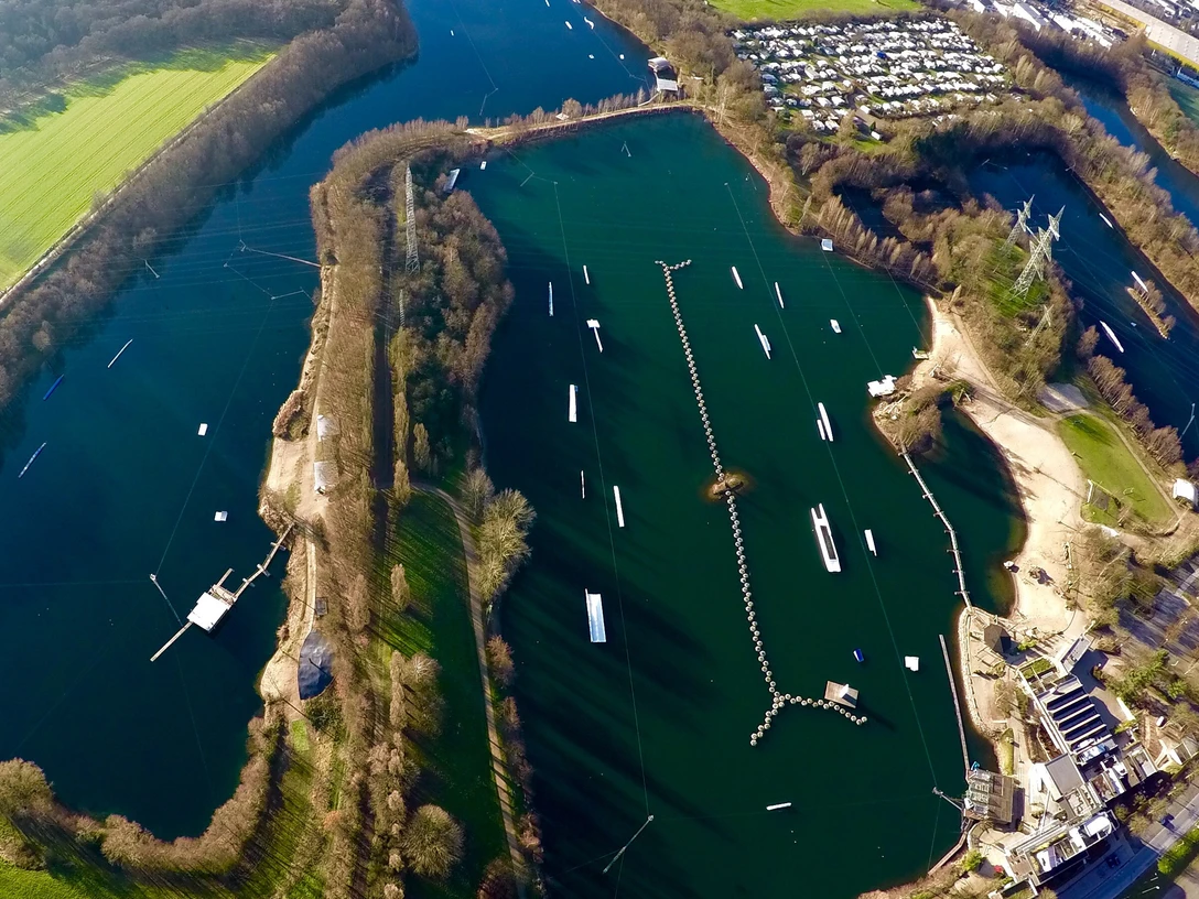 Anlage Wasserski-Langenfeld von oben mitsamt Campingplatz Wasserski-Anlage mit Seilbahnen auf Seen, umgeben von Bäumen; Campingplatz oben im Bild sichtbar.