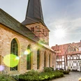 Kirche mit historischem Kirchhof und Fachwerkhäusern bei Sonnenschein im charmanten Dorf.