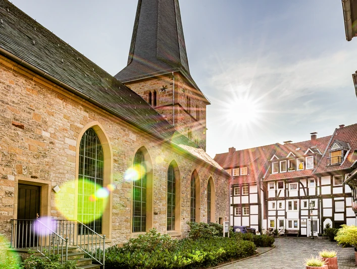 Kirche mit historischem Kirchhof und Fachwerkhäusern bei Sonnenschein im charmanten Dorf.
