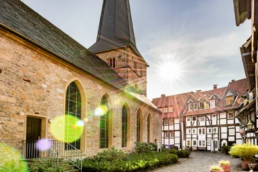 Kirchring-Apostelkirche-GT-M.Wallenfang (3).jpg Kirche mit historischem Kirchhof und Fachwerkhäusern bei Sonnenschein im charmanten Dorf.