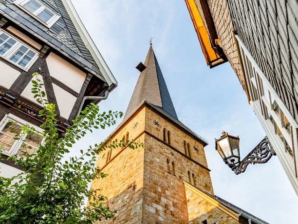 Fachwerkhäuser und Kirchturm in einem historischen deutschen Dorf unter blauem Himmel.
