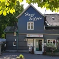 Haus Eifgen Gasthaus in einem blauen Fachwerkhaus, umgeben von grünen Bäumen, mit dem Schild "Haus Eifgen".