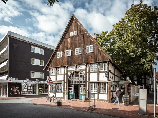 Buchhandlung Markus Fachwerkhaus mit Café in einem urbanen Umfeld, umgeben von Bäumen und Geschäften auf Kopfsteinpflaster.
