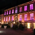 Alte Abtei im Lichterglanz von der Klosterpforte.jpg Historisches Gebäude bei Nacht mit violett beleuchteten Fenstern und festlich geschmücktem Eingang.