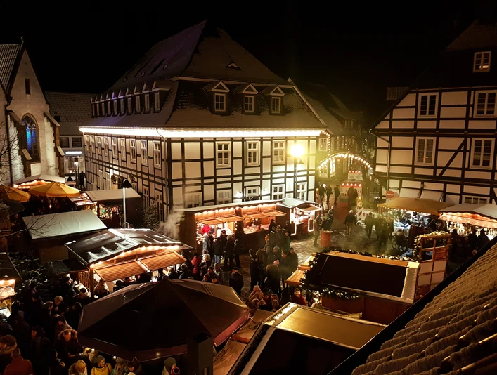 Adventsmarkt Rietberg Winterlicher Weihnachtsmarkt mit festlich beleuchteten Fachwerkhäusern und fröhlichen Menschen in Abenddämmerung.