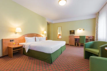 Doppelzimmer im Kapeller Hof in Langenfeld Helles, geräumiges Doppelzimmer mit grünem Teppich, Bett, Schreibtisch und zwei Leselampen.