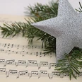 Weihnachtskonzert Notenzettel daneben ein Tannenzweig und einem glitzernden Stern.