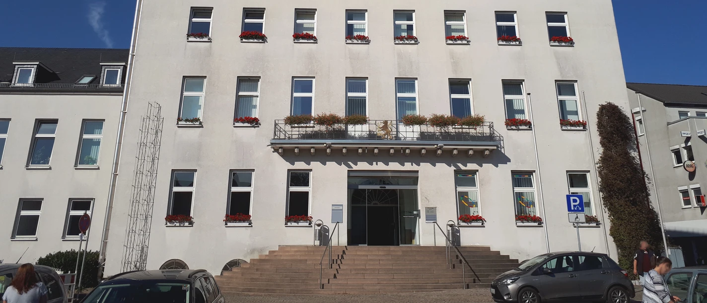 Rathaus Velbert Rathaus Velbert mit imposantem Turm, weißen Fassaden und rot-blühenden Fensterkästen bei blauem Himmel.