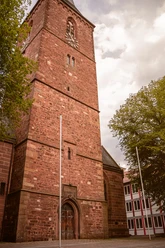 Backsteinkirche von St. Marien in Lügde mit markantem Turm, hellem Himmel und großen Bäumen.