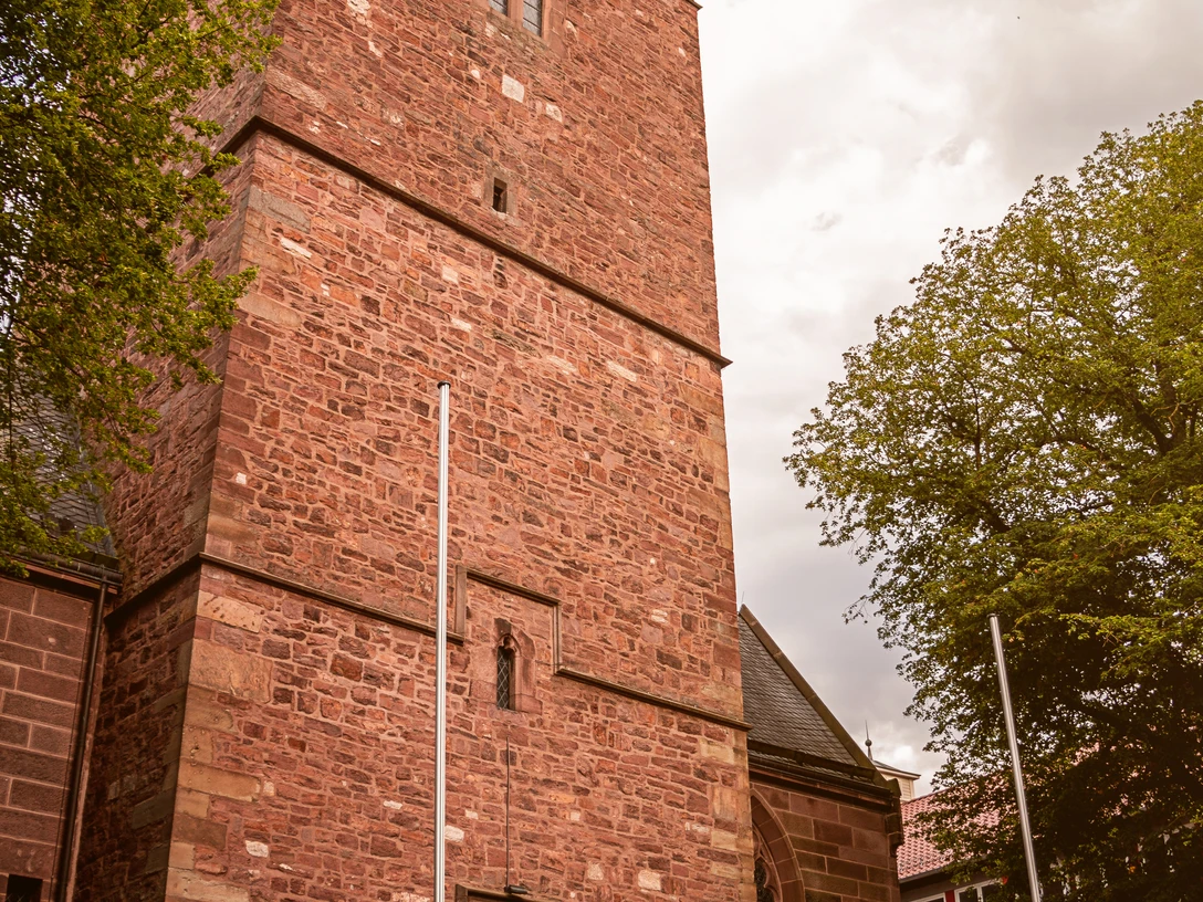 St. Marien Kirche Lügde Backsteinkirche von St. Marien in Lügde mit markantem Turm, hellem Himmel und großen Bäumen.
