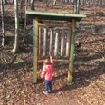Dendrophon Ein Kind spielt im Wald mit einem großen, stehenden Xylophon aus Holzstämmen, dem "Dendrophon".