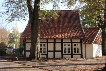 Cafe Klüter Fachwerkhaus mit roten Dachziegeln, umgeben von Laubbäumen, sonniger Herbsttag, Eingang sichtbar.