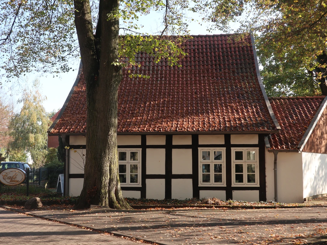 Cafe Klüter Fachwerkhaus mit roten Dachziegeln, umgeben von Laubbäumen, sonniger Herbsttag, Eingang sichtbar.