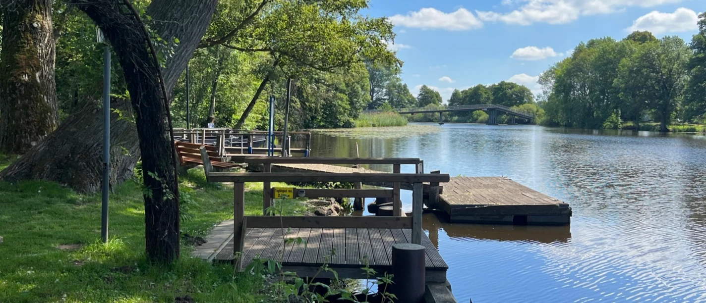 Anleger Melchers Hütte Holzanleger an der Hamme bei Melchers Hütte mit Blick auf Fluss, Bäume und Brücke im Hintergrund