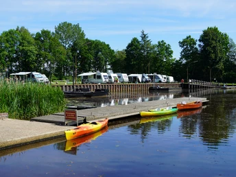 Kanuverleih am Hammehafen.JPG Mehrere bunte Kanus liegen am Holzsteg des Hammehafen, dahinter Wohnmobile und Bäume.
