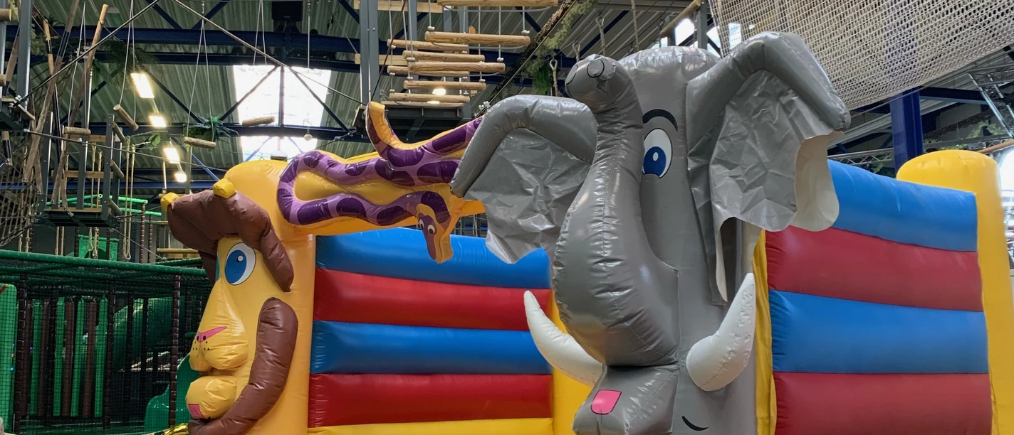 Hüpfburg im Okidoki Kinderland in Langenfeld Hüpfburg mit bunten Elementen und Tiermotiven, darunter ein Elefant und eine Giraffe, im Indoor-Spielbereich.