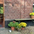 Bauernhof-Café Groß Ilbeck in Ratingen Eingang eines roten Backsteingebäudes mit offenen Holztüren, blühenden gelben Chrysanthemen in Körben.