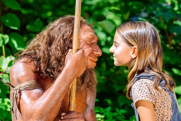 Gesichtervergleich mit MR N und Mädchen Ein Mädchen steht einem Neandertaler-Modell gegenüber, beide blicken sich intensiv in die Augen.