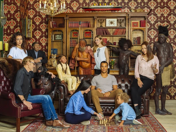 Menschenfamilie im Neanderthal Museum in Mettmann Im Neanderthal Museum posiert eine Gruppe von Menschen und künstlichen Figuren in einem historischen Raum.