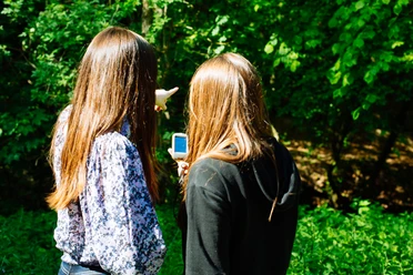 Geocaching im Neandertal Zwei Personen erkunden mit einem Navigationsgerät einen Wald, umgeben von üppigem Grün.