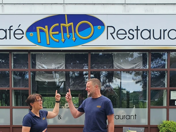 Restaurant Nemo Otterndorf Fröhliche Gastgeber vor der modernen Glasfassade des Restaurants Café Nemo in Otterndorf.