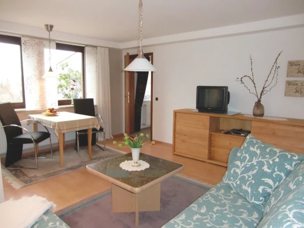 Wohnzimmer mit Esstisch und Sofa in der Ferienwohnung Falkenhöhe.