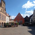 Ein belebter Platz in Lemgo mit historischen Fachwerkhäusern und zahlreichen Besuchern bei Sonnenschein.