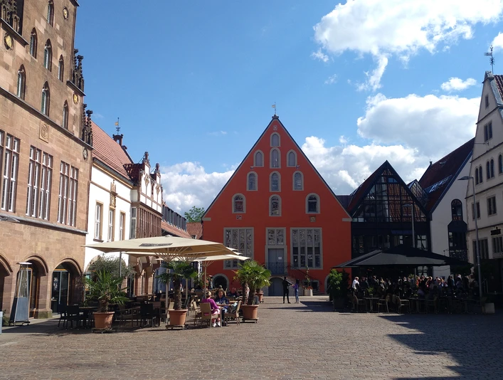 Ein belebter Platz in Lemgo mit historischen Fachwerkhäusern und zahlreichen Besuchern bei Sonnenschein.