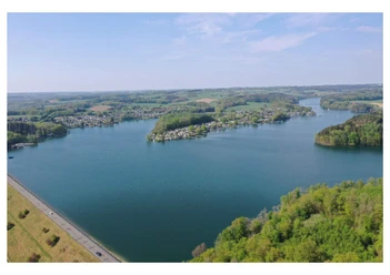 Campingpark Luftaufnahme eines großen, blauen Sees, umgeben von grünen Wäldern und kleinen Siedlungen.