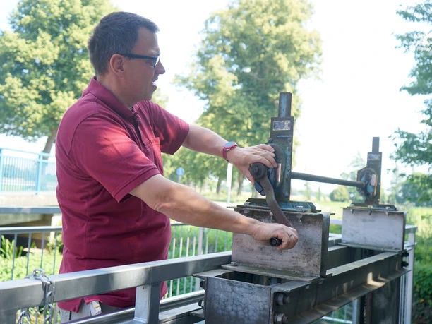 Von Hand stoppt Andres Jansen den Wasserzufluss, damit das Mühlenrad stehen bleibt.