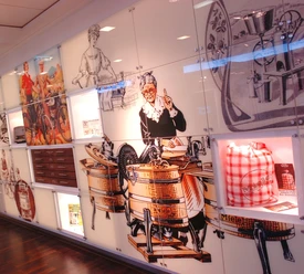2006-206_06.jpg Retro-Illustrationen alter Miele-Waschmaschinen verzieren eine moderne weiße Wand in einem Ausstellungsraum.