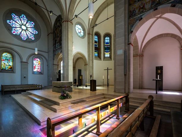 St.Pankratius Kirche Innenansicht einer Kirche mit bunten, leuchtenden Glasfenstern, einer Kanzel und Altartischen.