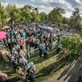 Freitag 18 Dreiecksplatz Eine große Menschenmenge versammelt sich bei einem sonnigen Freiluft-Event in einem grünen Park.