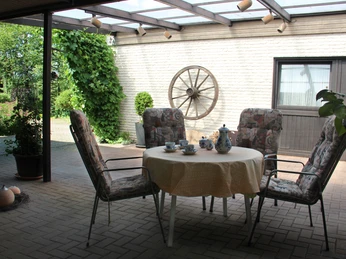 054_Pergola2.jpg Ein gemütlicher Innenhof mit einem Tisch und Stühlen, dekoriert für einen entspannten Teegenuss.