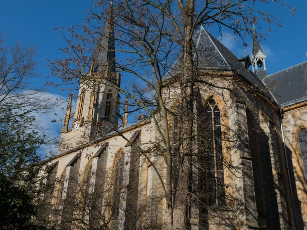 Martin-Luther-Kirche Gotische Kirche mit hohen Fenstern und spitzem Turm, umgeben von kahlen Bäumen, blauer Himmel.
