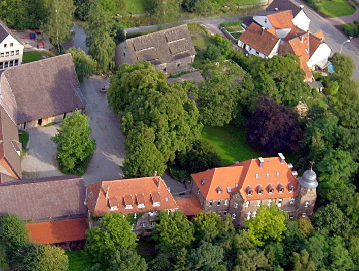 Burg Borgholz Luftbild der historischen Burg Borgholz mit umliegenden Gebäuden und dichtem Baumbestand.