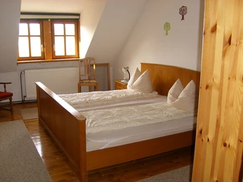 Burg Borgholz - Doppelzimmer Doppelzimmer mit Holzbett und zwei Kopfkissen, Schreibtisch, Stuhl und Fenster im Hintergrund.