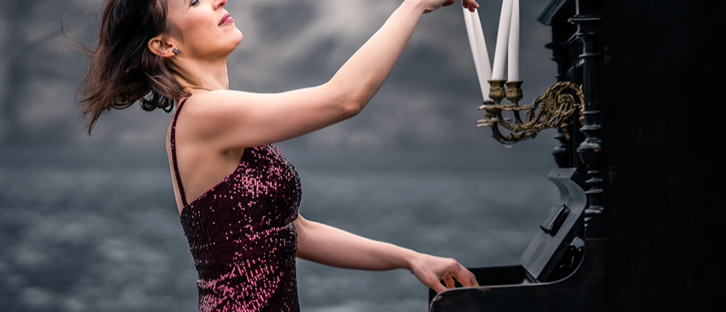 Weltklassik: Nadejda Vlaeva Pianistin Nadejda Vlaeva im roten Paillettenkleid am Klavier, welches mit weißen Kerzen dekoriert ist.