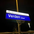 Ein nachts beleuchtetes Bahnhofsschild mit der Aufschrift "Reiterstadt Verden (Aller)".