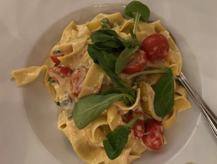 Ein Teller mit Bandnudeln, garniert mit frischem Rucola und Kirschtomaten in einer cremigen Sauce.A plate of tagliatelle garnished with fresh rocket and cherry tomatoes in a creamy sauce.En tallerken tagliatelle garneret med frisk rucola og cherrytomater i en cremet sauce.Een bord tagliatelle gegarneerd met verse rucola en kerstomaatjes in een romige saus.