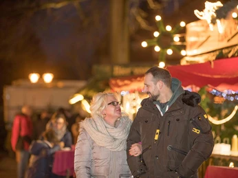 markt-im-advent-bummeln.jpg Paar spaziert abends über festlich beleuchteten Adventsmarkt mit Lichtern und Ständen.Couple strolls through a festively lit Advent market with lights and stalls in the evening.Et par slentrer gennem et festligt oplyst adventsmarked med lys og boder om aftenen.Paar wandelt 's avonds over een feestelijk verlichte adventsmarkt met lichtjes en kraampjes.