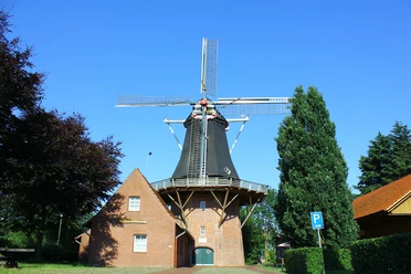 Heimathaus Werlte.jpg Historische Windmühle aus rotem Backstein mit schwarzem Turm und Flügeln vor blauem Himmel