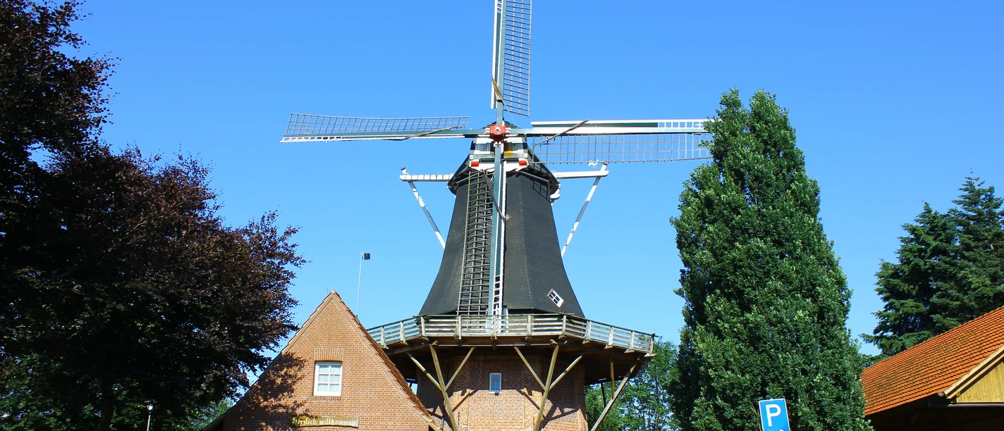 Heimathaus Werlte.jpg Historische Windmühle aus rotem Backstein mit schwarzem Turm und Flügeln vor blauem Himmel