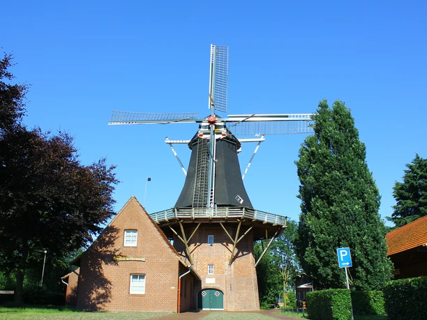 Heimathaus Werlte.jpg Historische Windmühle aus rotem Backstein mit schwarzem Turm und Flügeln vor blauem Himmel